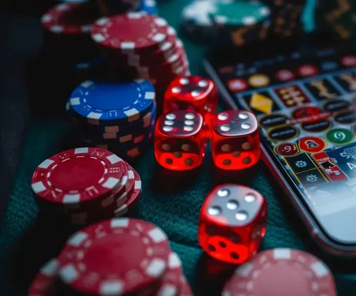 Fichas de cassino e dados vermelhos sobre a mesa ao lado de um celular